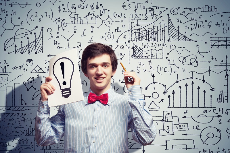 Image of thoughtful male student holding notebook in classroom
