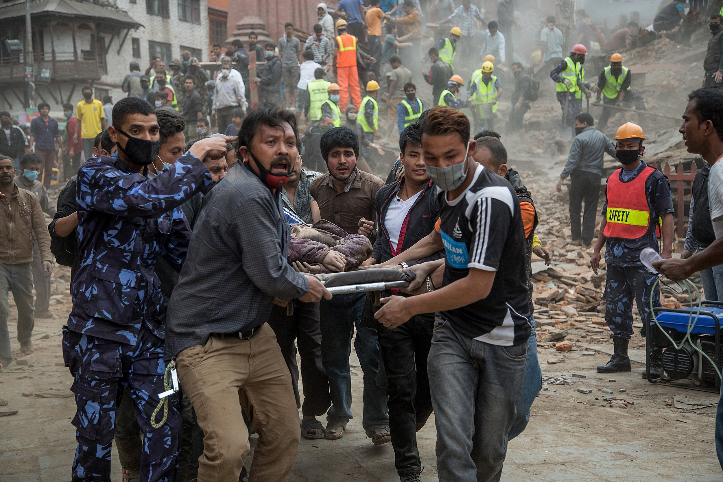 KATHMANDU, NEPAL - APRIL 25: Emergency rescue workers carry a victim on a stretcher after Dharara tower collapsed on April 25, 2015 in Kathmandu, Nepal. More than 100 people have died as tremors hit Nepal after an earthquake measuring 7.9 on the Richter scale caused buildings to collapse and avalanches to be triggered in the Himalayas. Authorities have warned that the death toll is likely to be much higher. (Photo by Omar Havana/Getty Images)