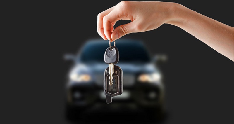 womans-hand-holding-car-keys-in-front-of-car-mst