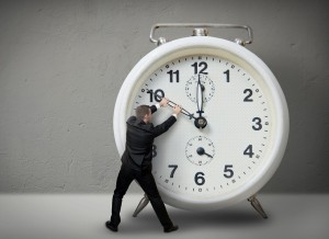 Businessman pulling a clock hand backwards,time