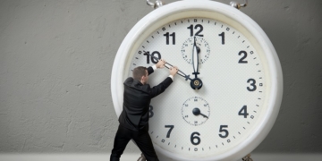 Businessman pulling a clock hand backwards,time