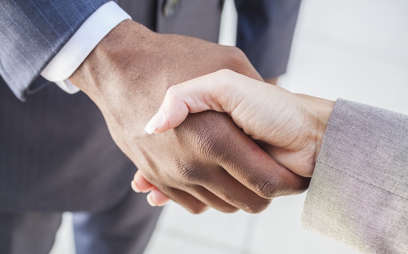 African American businessman or man shaking hands with a businesswoman or woman caucasian female colleague making a business deal