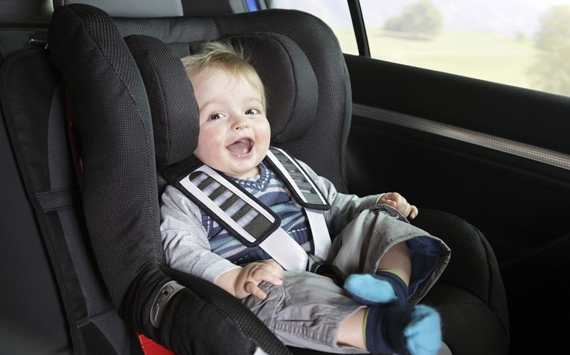Safety in the car - Smiling baby boy safely sitting in a car seat