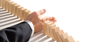 businessman-interrupting-wooden-dominoes