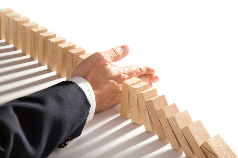 businessman-interrupting-wooden-dominoes