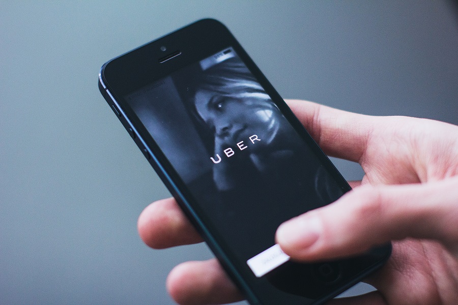 χερι που κραταει κινητό στο οποίο φαίνεται η μάρκα uber και μια γυναίκα