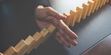 Problem Solving,Close up view on hand of business woman stopping falling blocks on table for concept about taking responsibility.