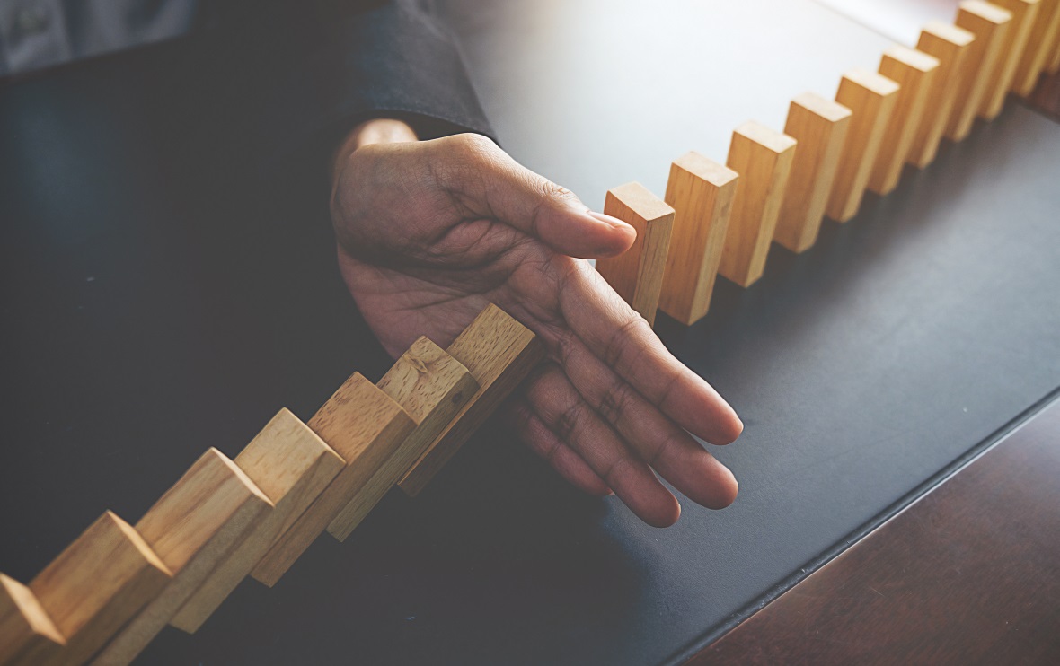 Problem Solving,Close up view on hand of business woman stopping falling blocks on table for concept about taking responsibility.