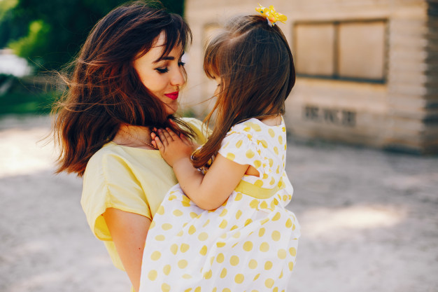 on-a-sunny-beach-with-yellow-sand-mom-walks-in-a-yellow-dress-and-her-little-pretty-girl