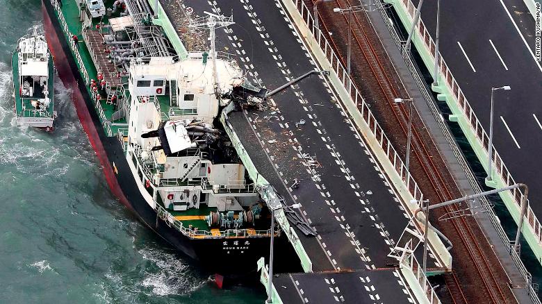A tanker is seen after it slammed into the side of a bridge connecting the airport to the mainland, damaging part of the bridge and the vessel in Osaka, western Japan, Tuesday, Sept. 4, 2018. A powerful typhoon blew through western Japan on Tuesday, causing heavy rain to flood the region's main offshore international airport and high winds to blow a tanker into a connecting bridge, disrupting land and air travel. (Kentaro Ikushima/Mainichi Newspaper via AP)