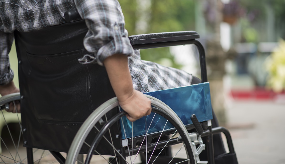 Close-up of senior woman hand on wheel of wheelchair during walk in hospital