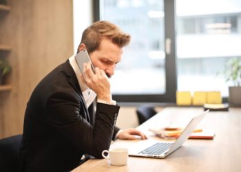 man-having-a-phone-call-in-front-of-a-laptop-insurancedaily