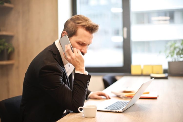 man-having-a-phone-call-in-front-of-a-laptop-insurancedaily