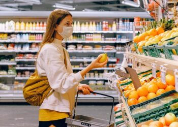 woman-in-yellow-tshirt-and-beige-jacket-holding-a-fruit-insurancedaily