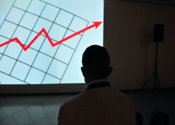 A man in front of a screen with a red arrow