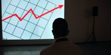 A man in front of a screen with a red arrow