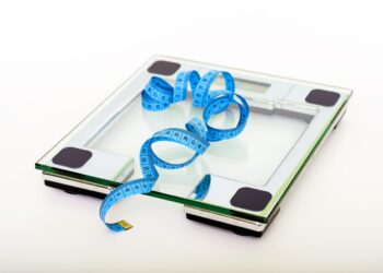 blue-tape-measuring-on-clear-glass-square-weighing-scale