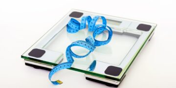 blue-tape-measuring-on-clear-glass-square-weighing-scale