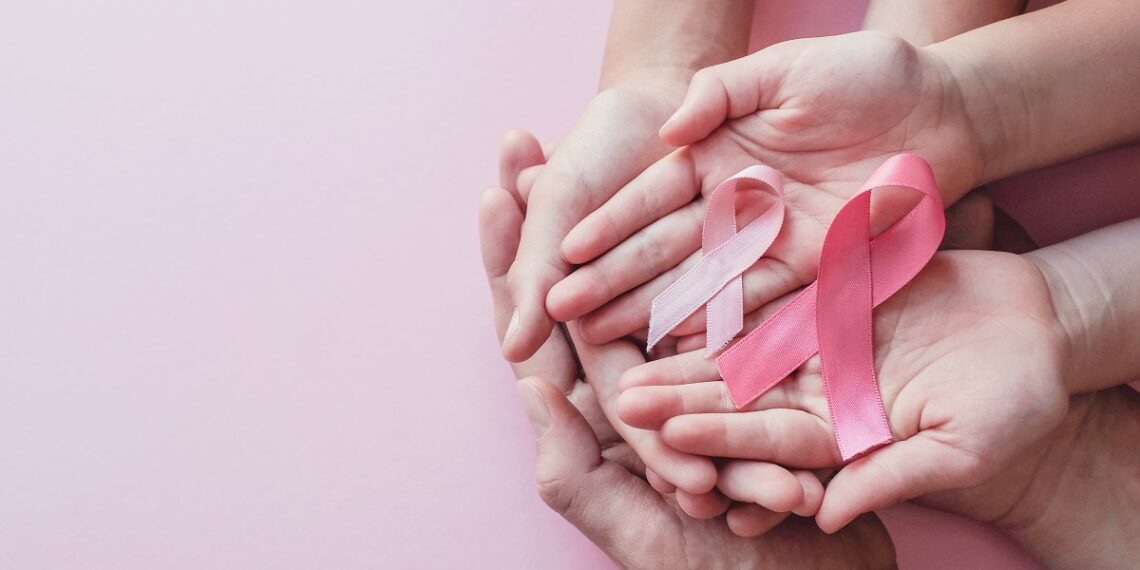 hands holding pink ribbons on pink background, Breast cancer awareness and October Pink day