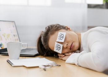 tired-businesswoman-covering-her-eyes-with-drawn-eyes-paper