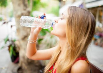 tired-female-tourist-drinking-water-outdoors
