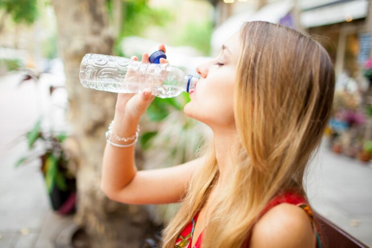 tired-female-tourist-drinking-water-outdoors
