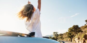 woman-car-road-trip-waving-out-window-smiling