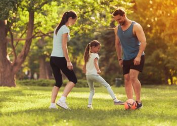 parents-daughter-play-football-in-park