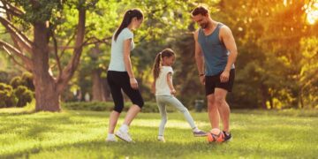 parents-daughter-play-football-in-park