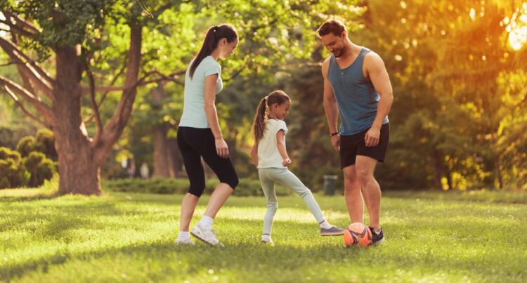 parents-daughter-play-football-in-park