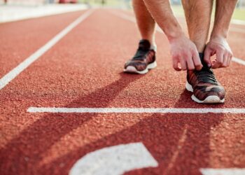 close-up-young-woman-tying-sports-shoe-red-race-track