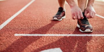 close-up-young-woman-tying-sports-shoe-red-race-track