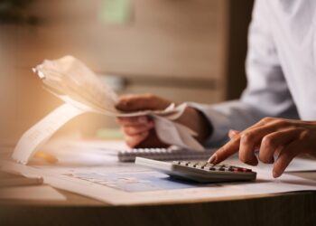 closeup-economist-using-calculator-while-going-through-bills-taxes-office