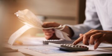 closeup-economist-using-calculator-while-going-through-bills-taxes-office