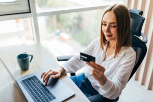 portrait-woman-holding-credit-card-using-laptop-home