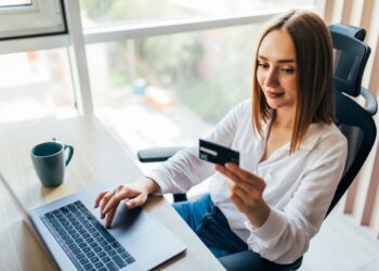 portrait-woman-holding-credit-card-using-laptop-home