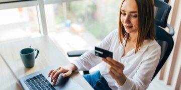 portrait-woman-holding-credit-card-using-laptop-home