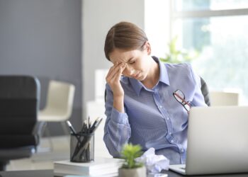 Young woman suffering from headache in office
