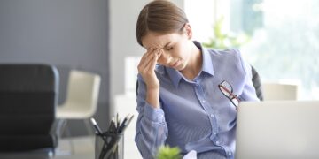 Young woman suffering from headache in office