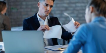 bossy-manager-tearing-apart-business-reports-front-his-female-colleague-office