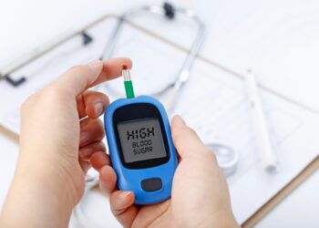 hand-holding-blood-glucose-meter-measuring-blood-sugar-background-is-stethoscope-chart-file
