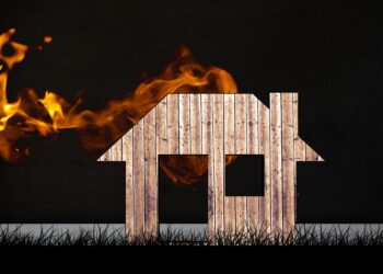 composite of burning house graphic on black grass