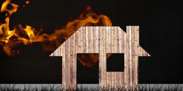 composite of burning house graphic on black grass