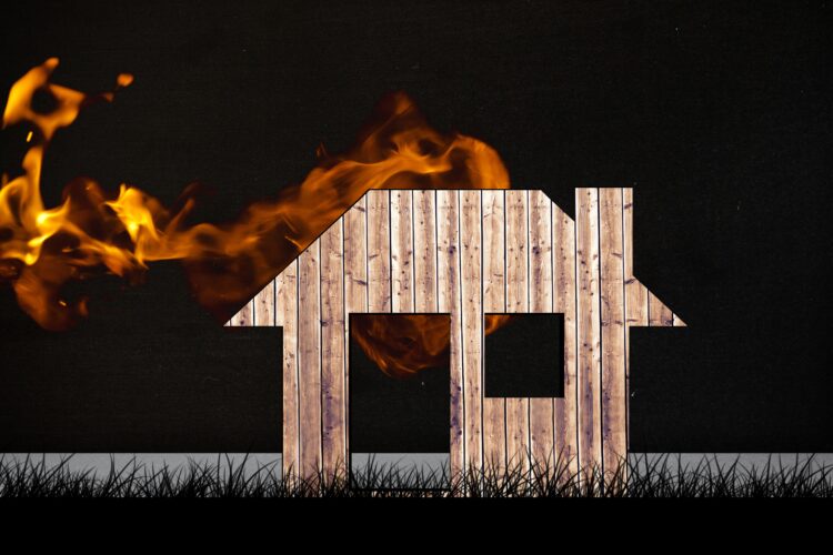 composite of burning house graphic on black grass