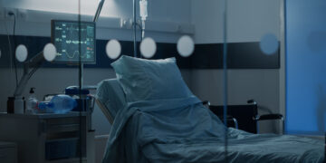 Hospital ward with empty bed at clinical facility for health problems treatment, surgery recovery and intensive care. Nobody in emergency room designed with equipment for healing